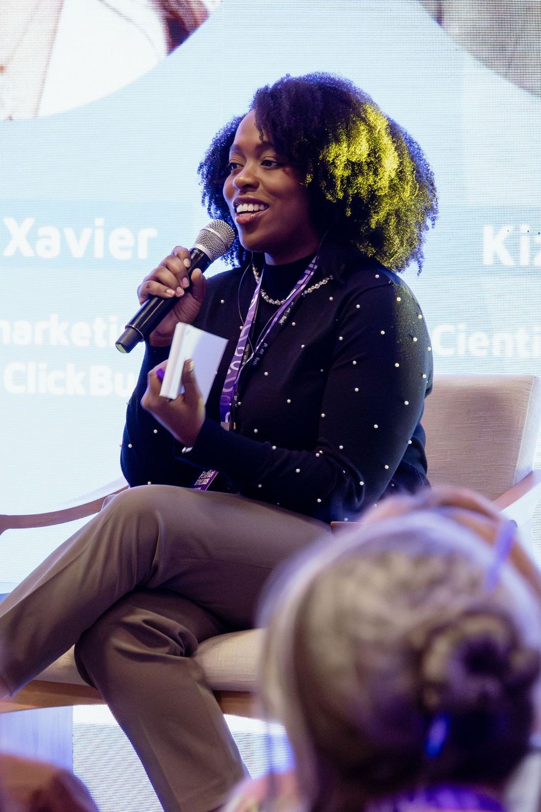 Kizzy Terra falando ao microfone durante um painel